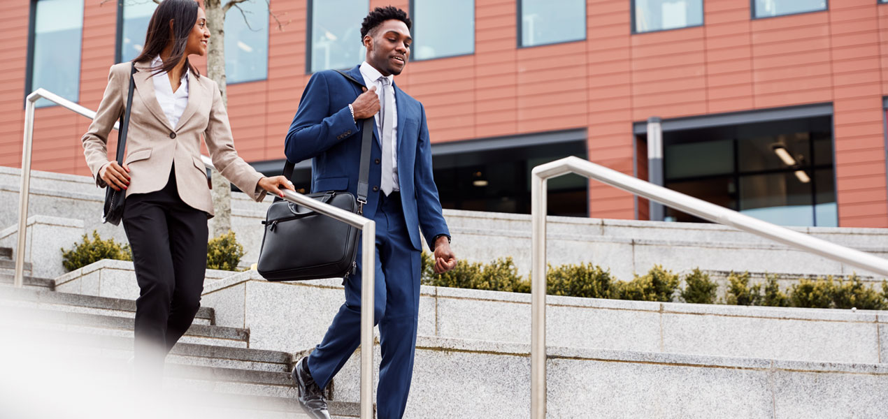 Business man and business woman walking down a set of stairs outside.