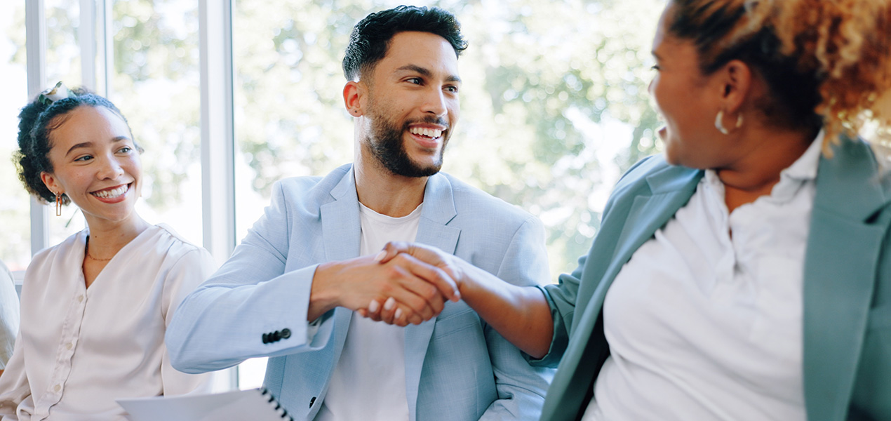 Two people in a waiting area shaking hands and introducing themselves.